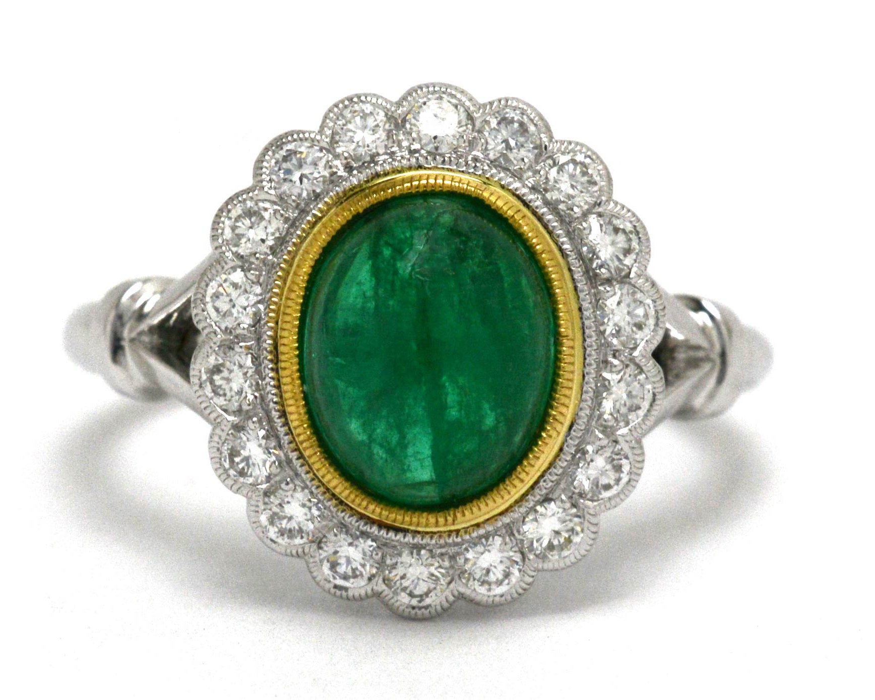 An Edwardian style emerald and diamond halo Princess Diana ring.