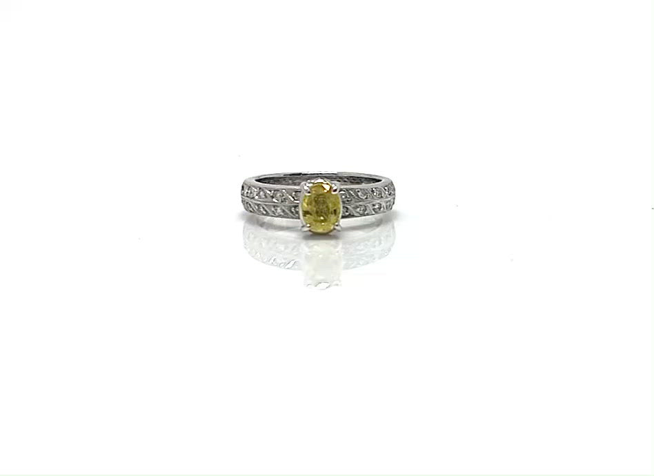 An oval yellow sapphire engagement ring with two rows of diamonds lined on the band.