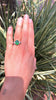 An oval, vivid and rich medium green emerald and diamonds engagement ring.