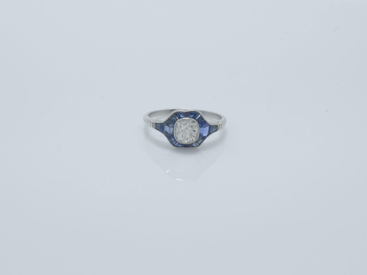 A 1 carat old mine cushion diamond wedding ring with French cut blue sapphires in the halo.