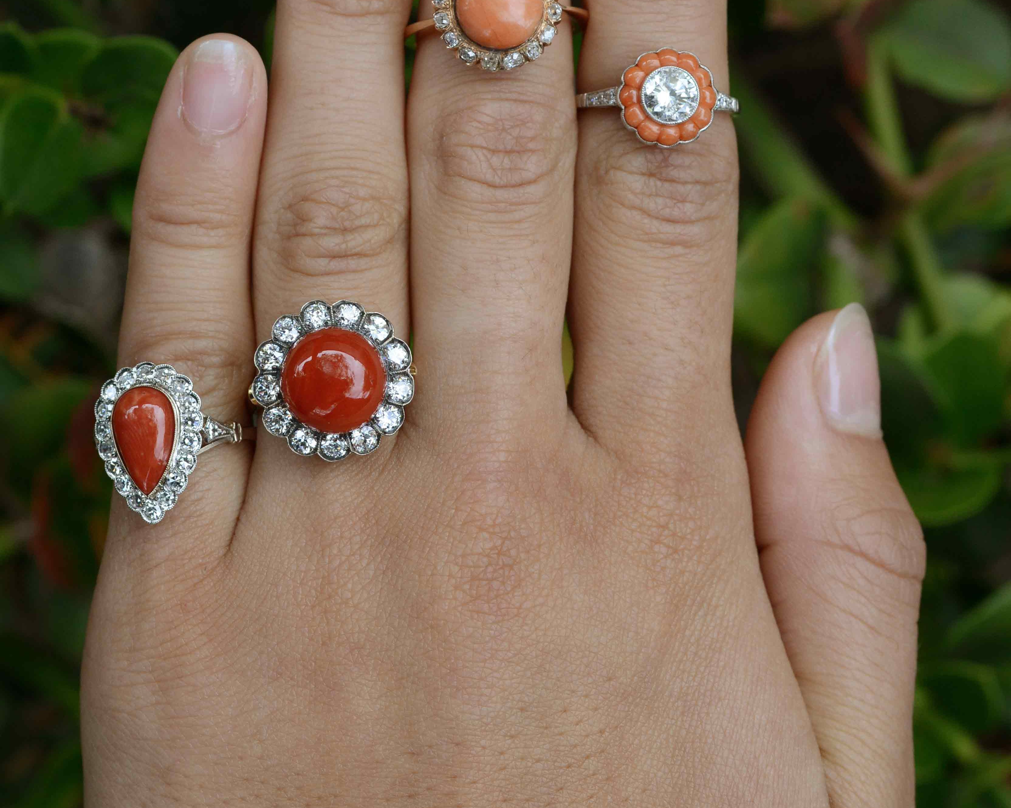 Round coral diamond halo statement rings.