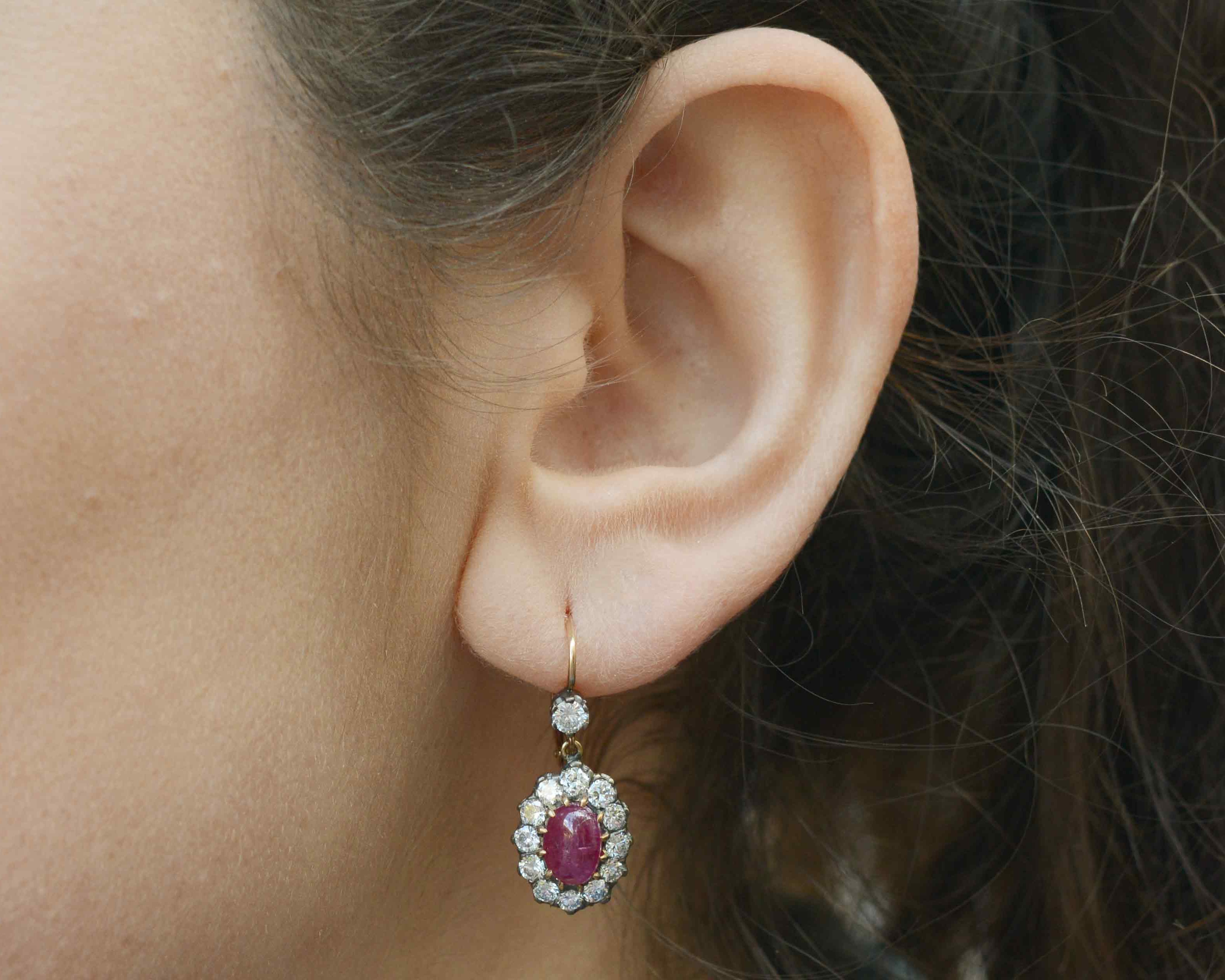 Oval rubies target leverback earrings surrounded by round diamonds.