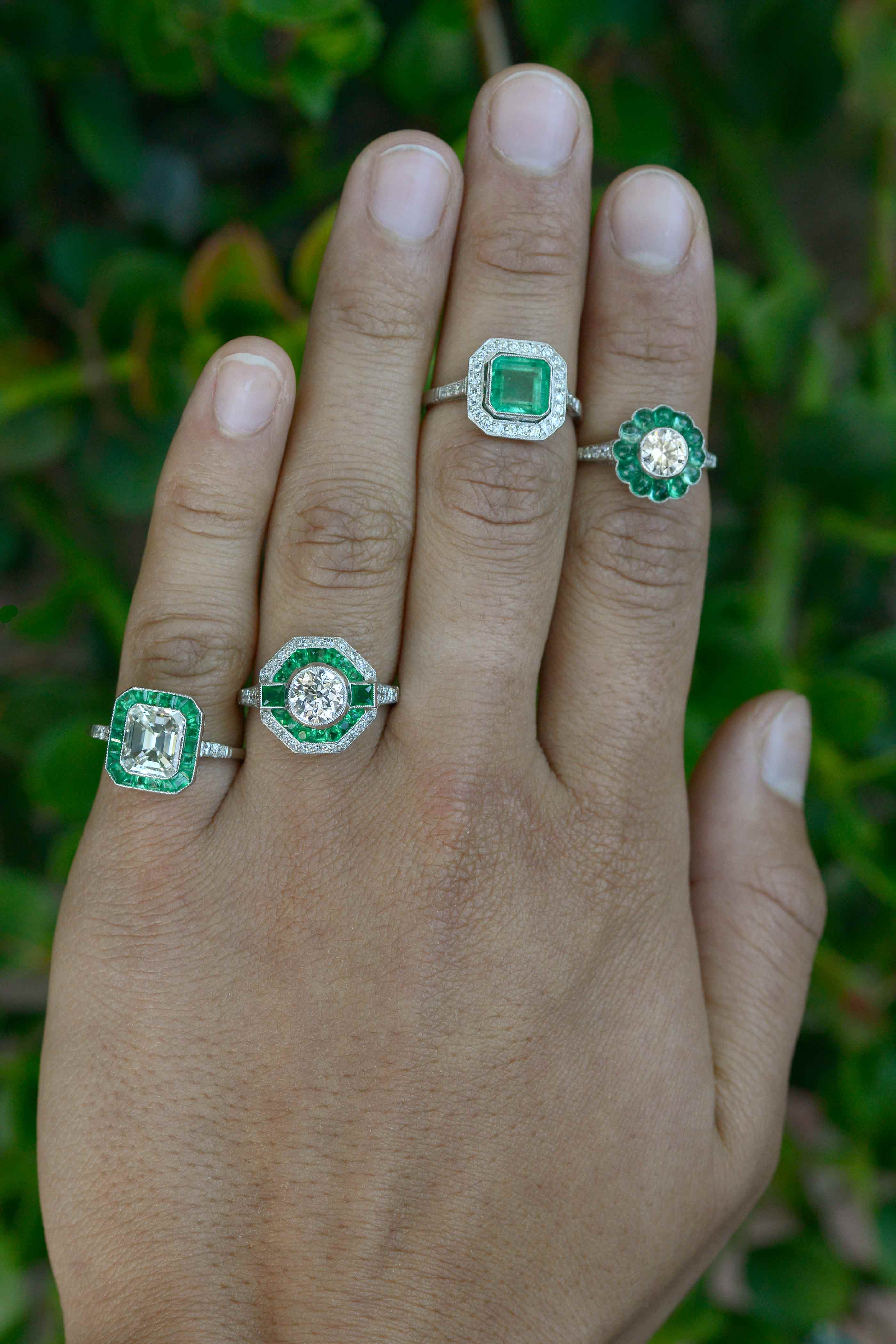 A collection of vintage and Art Deco style diamond and emerald halo engagement rings.