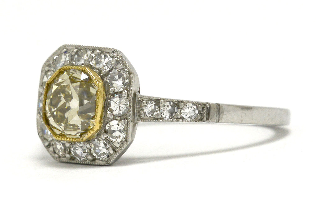 An old mine cushion diamond of light yellow color, set in a platinum ring.