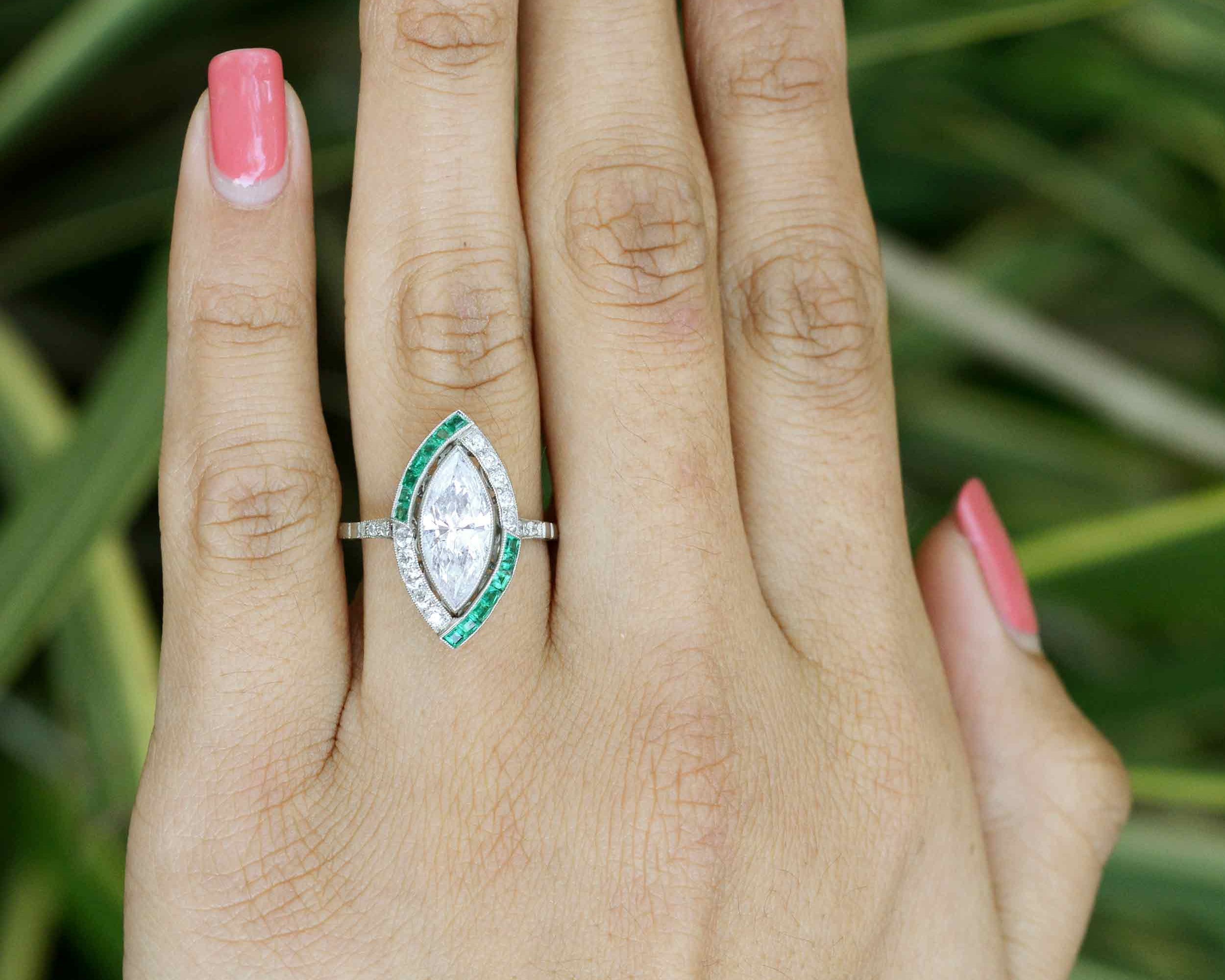 A unique marquise diamond and emerald engagement ring with a split halo pattern.