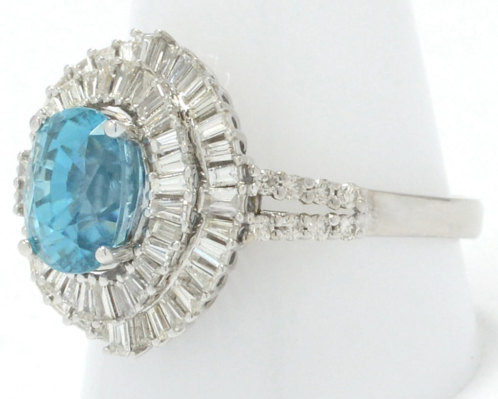 This statement ring has 2 halos of diamonds surround this large oval blue zircon.