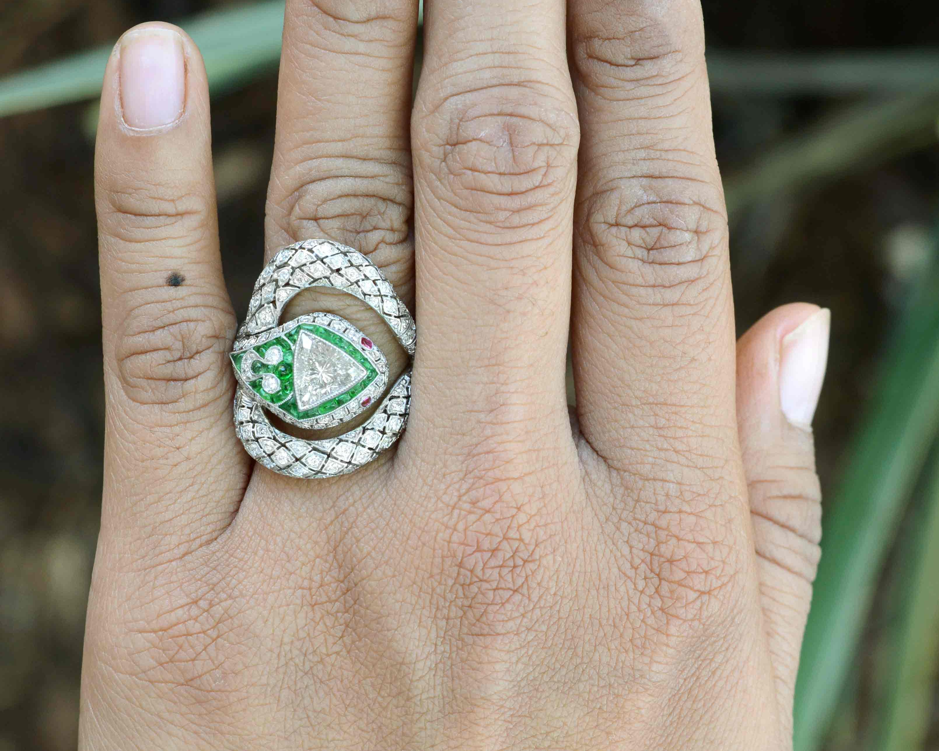 An Art Deco platinum snake diamond, emerald and rubies ring.