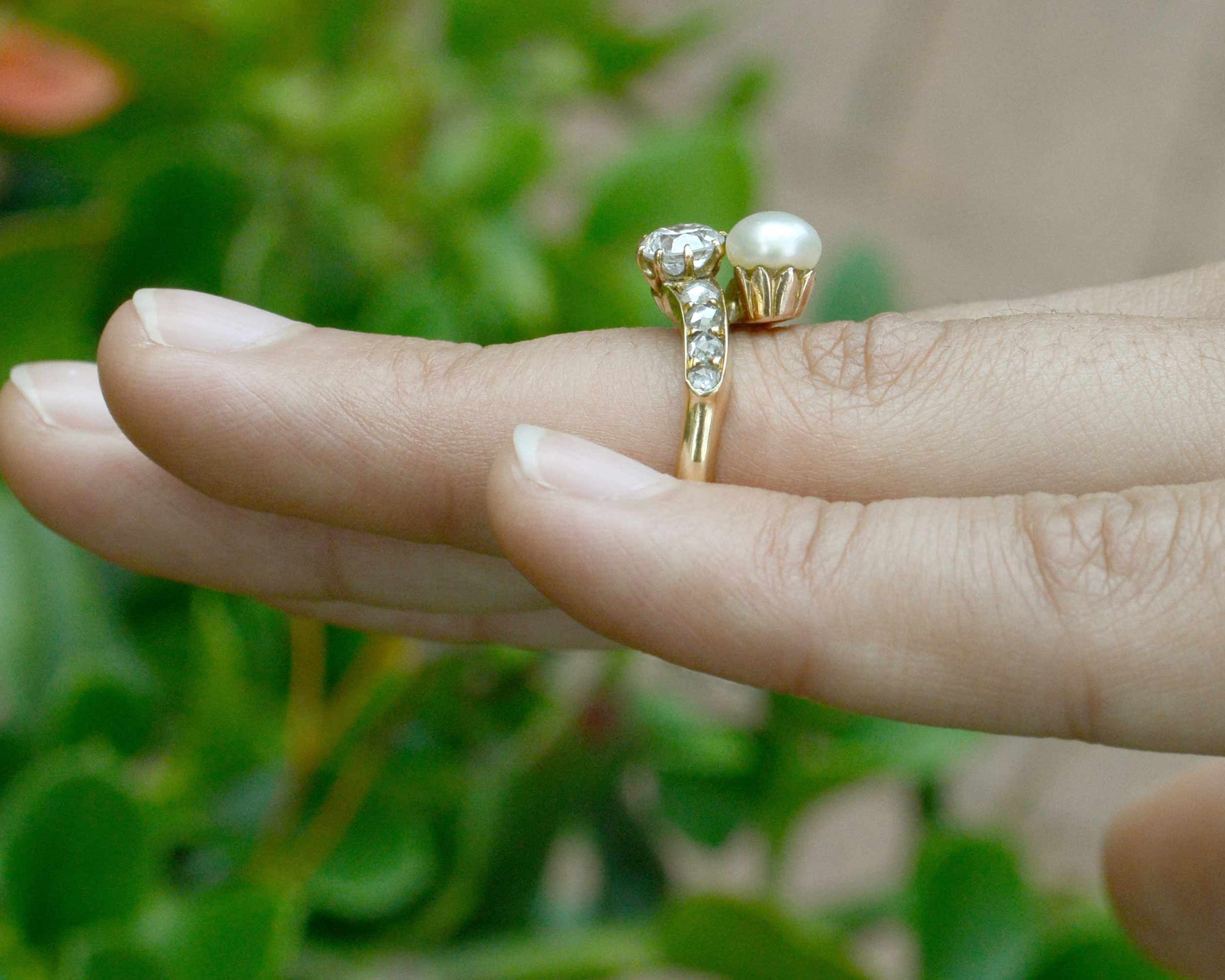 This gold wedding ring features a diamond and pearl in the center.