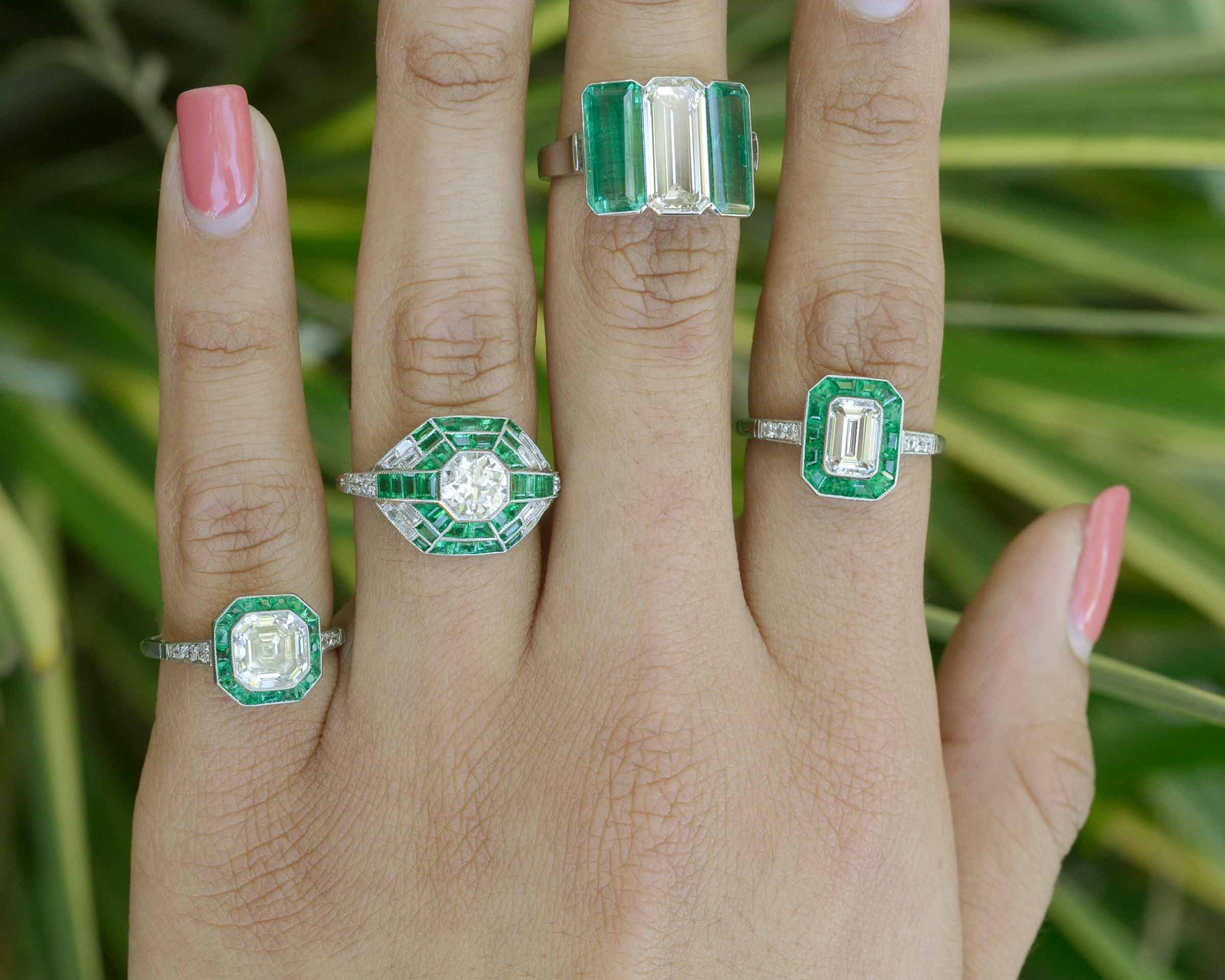 These engagement rings feature a large diamond and several emerald accent gemstones.
