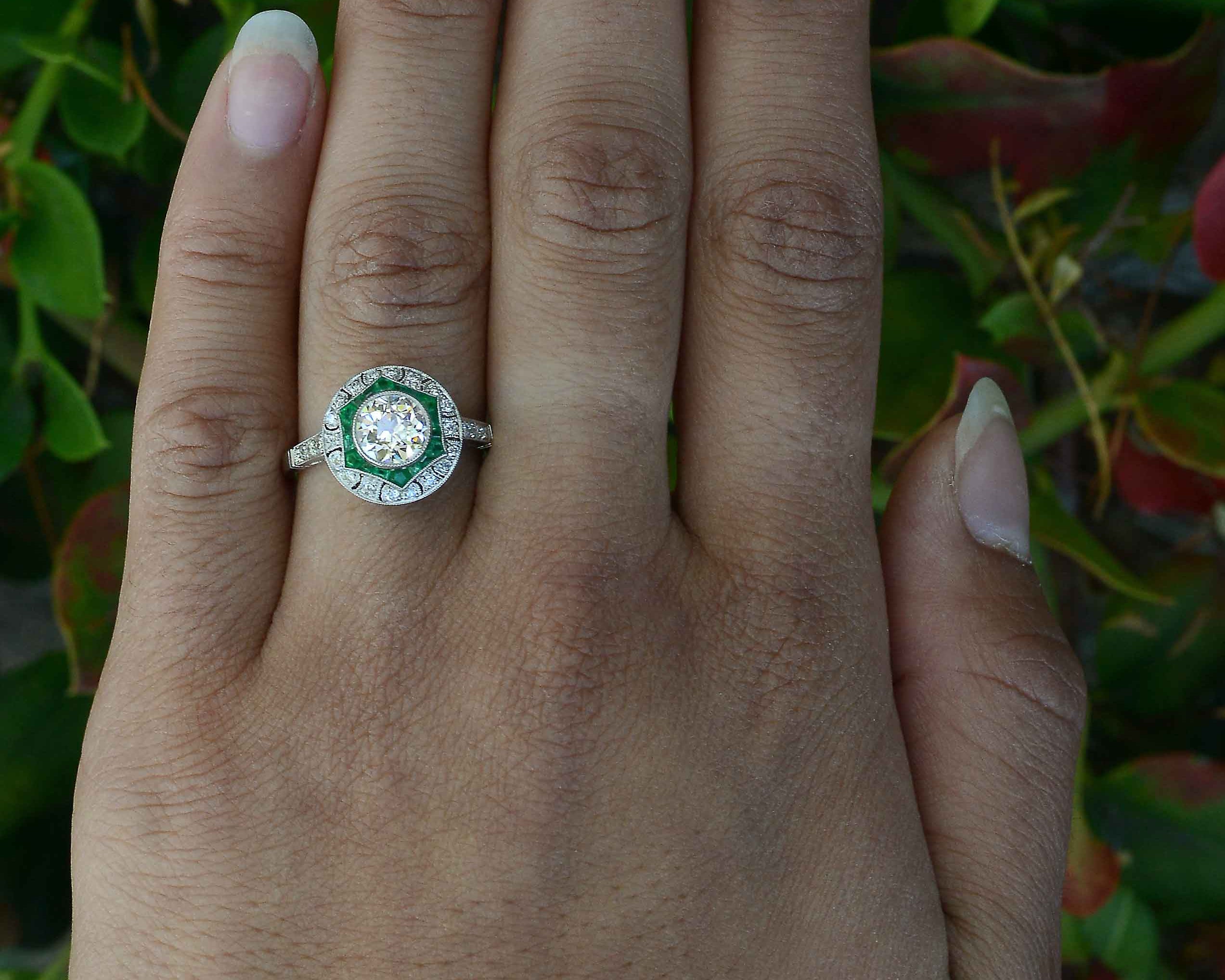 A diamond and emerald star design platinum engagement ring.