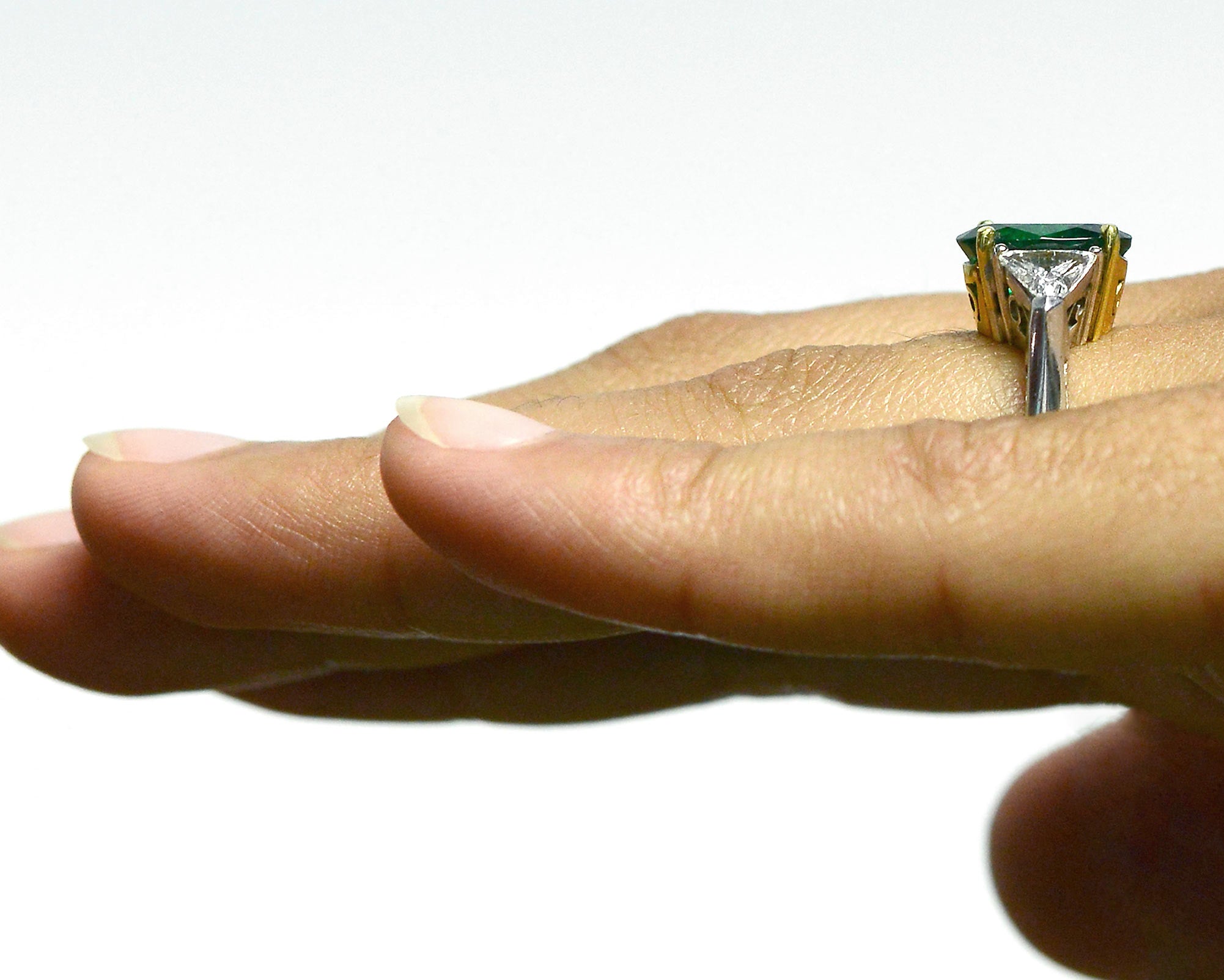 2 triangle diamonds accent the large oval emerald in this engagement ring.