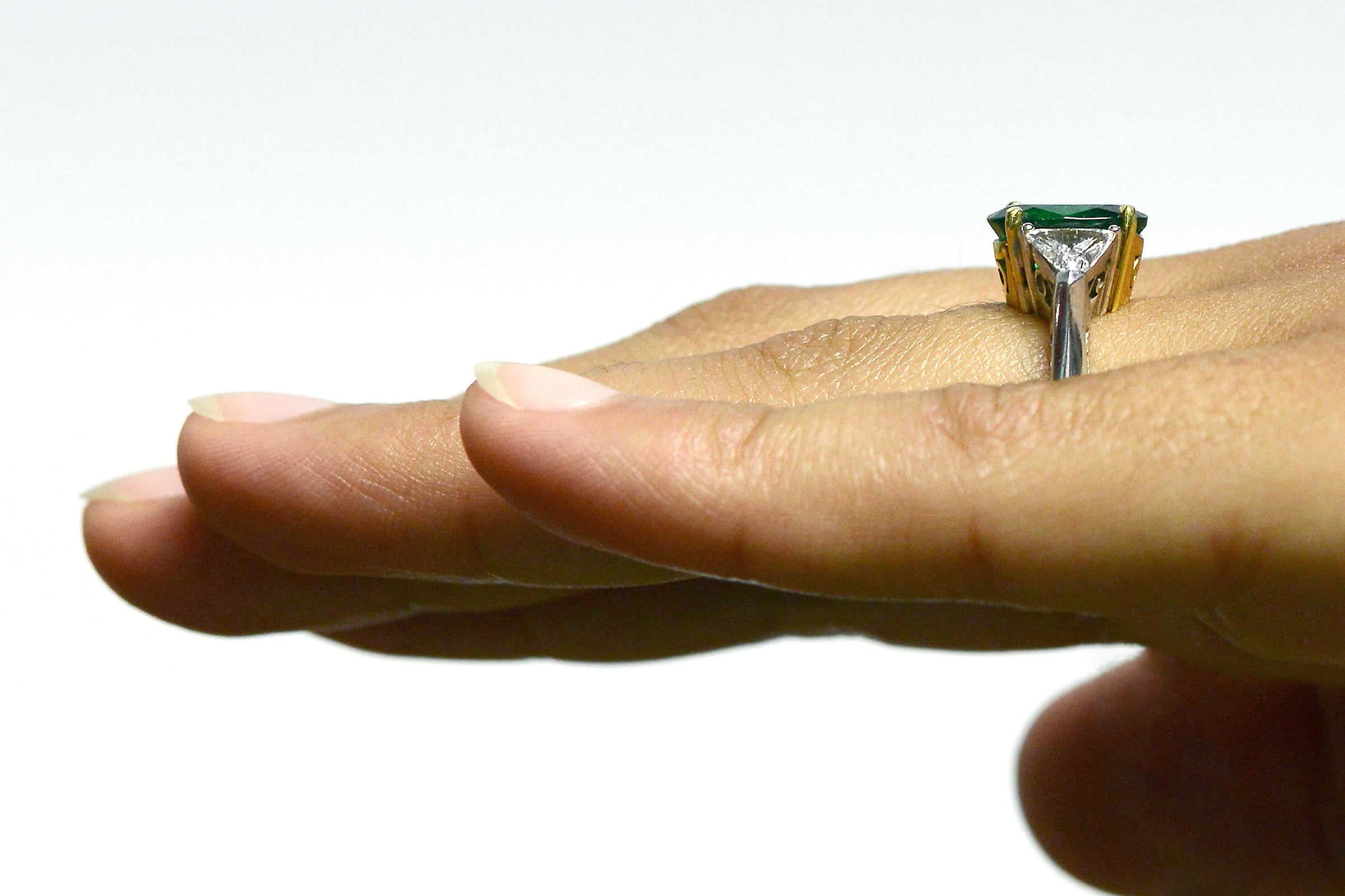 2 triangle diamonds accent the large oval emerald in this engagement ring.