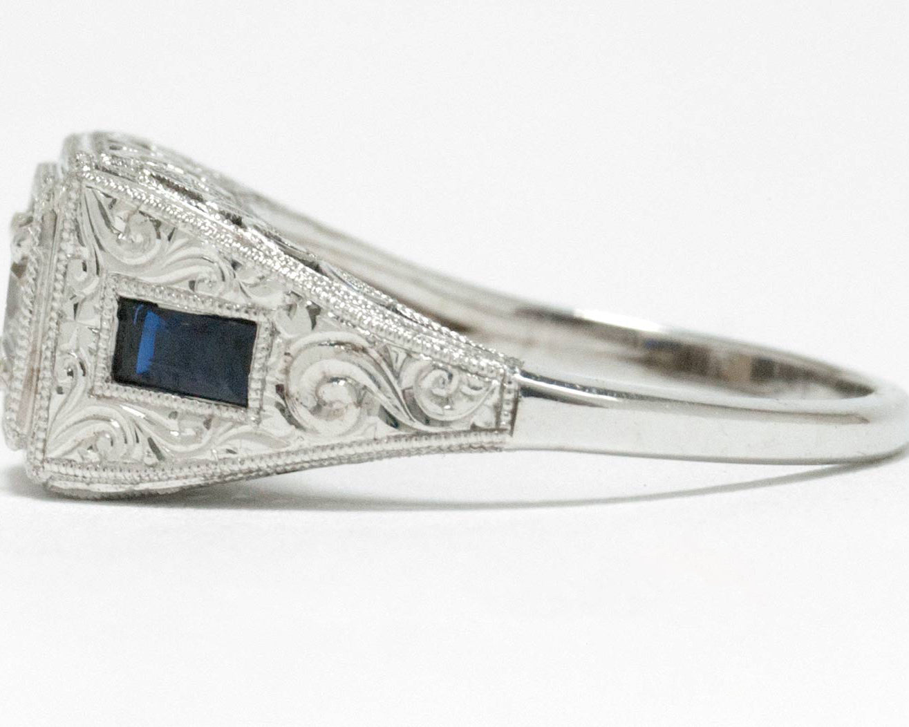 Engraved white gold scrolls on the side of this diamond blue sapphire engagement ring.