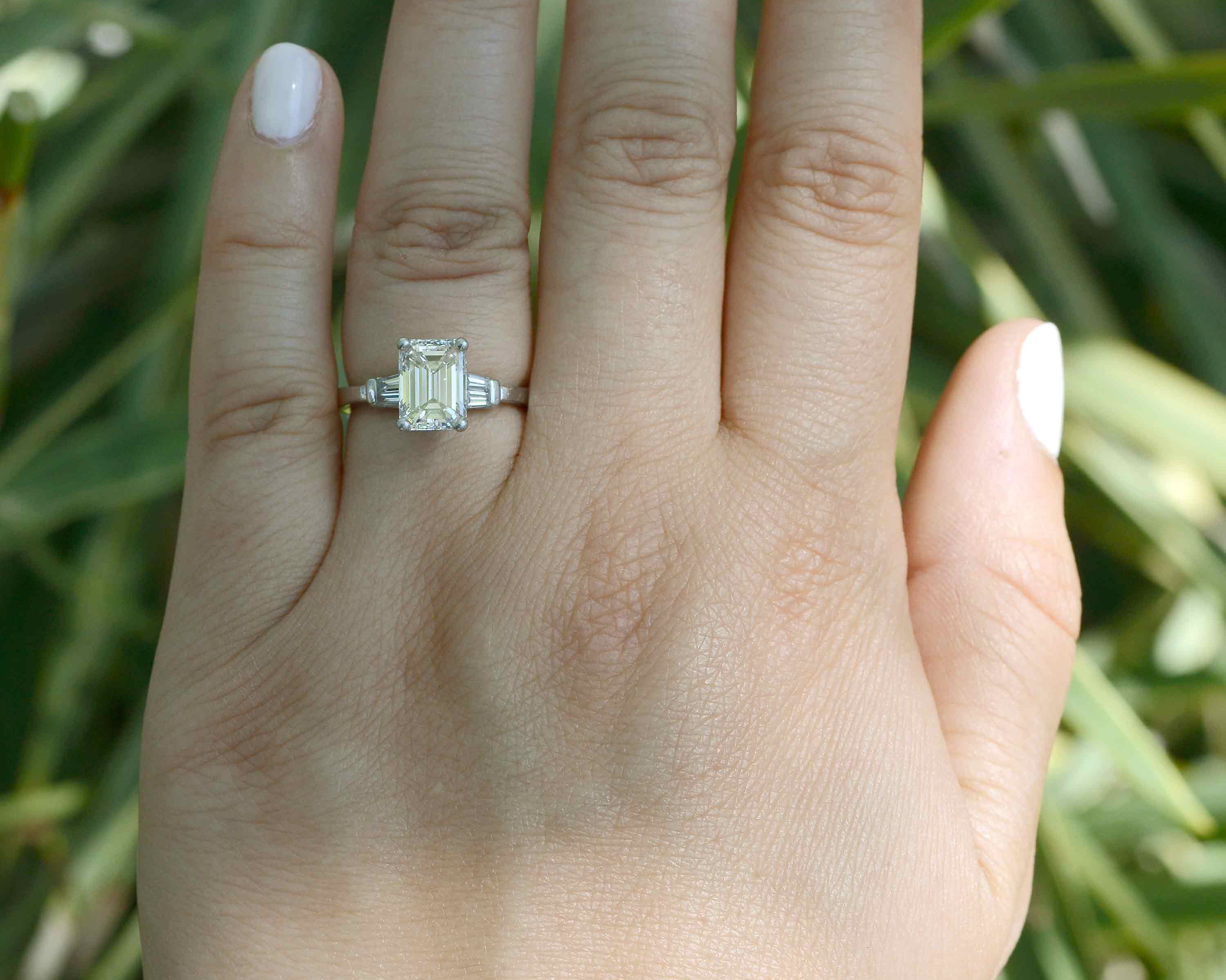 The center two carat emerald-cut diamond has an exquisite brilliance and liveliness.