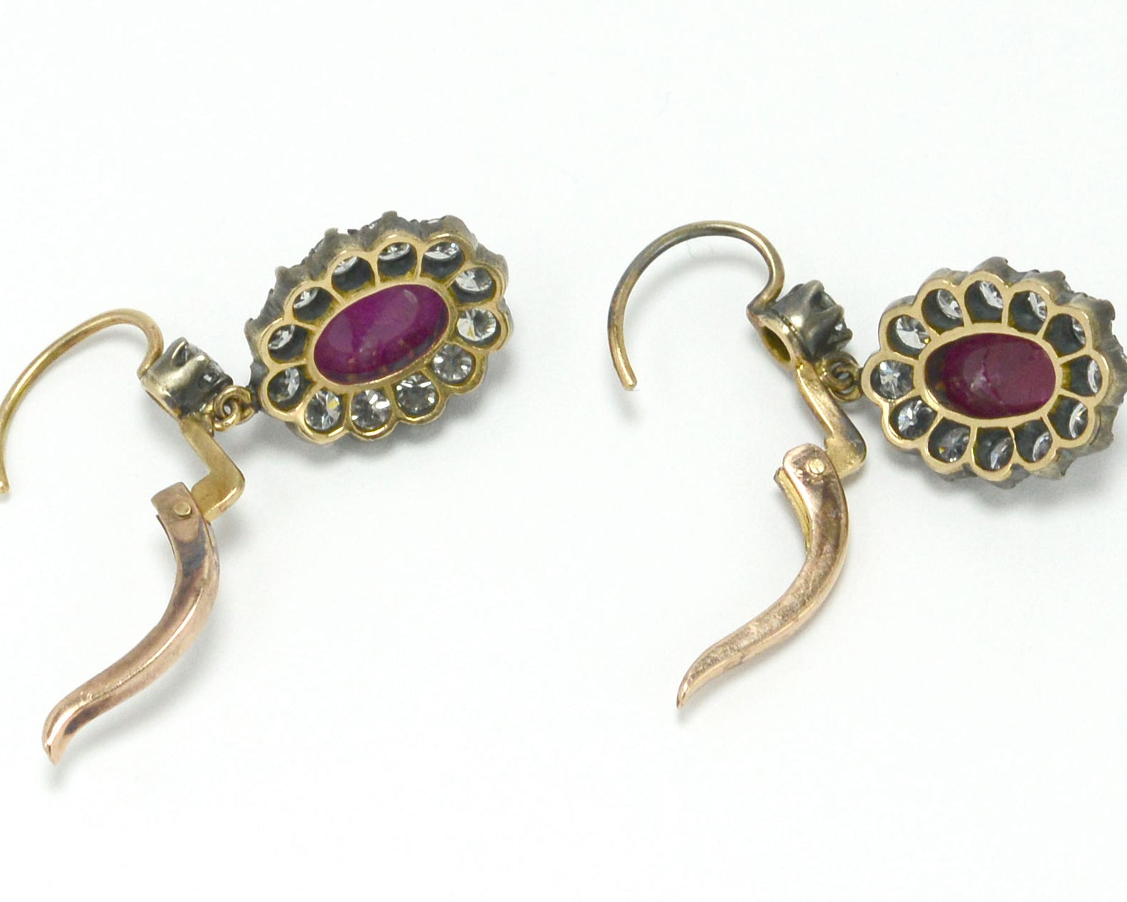 Silver topped 18k gold oval ruby diamond cluster earrings.