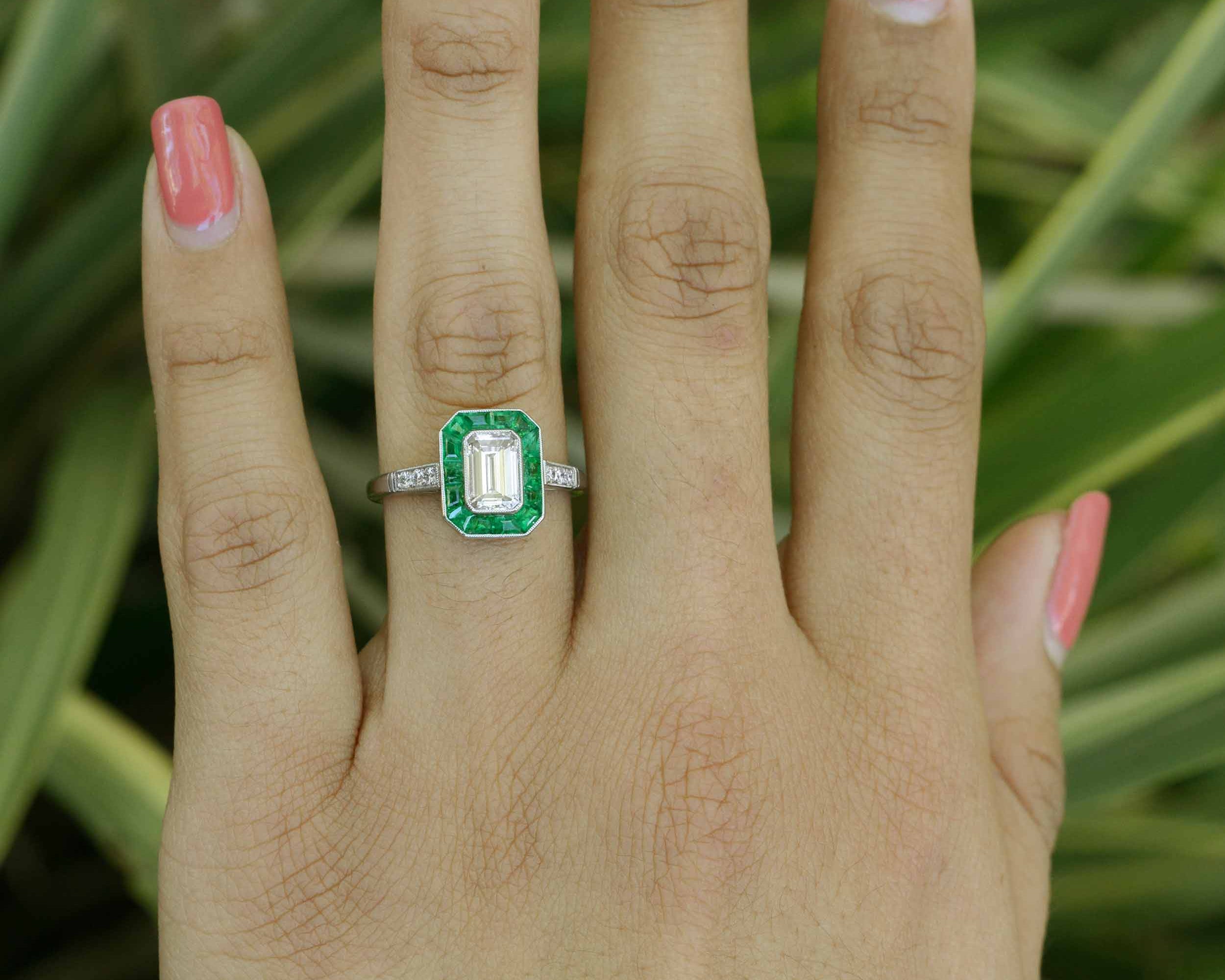 French cut emeralds surround the one carat emerald cut diamond.