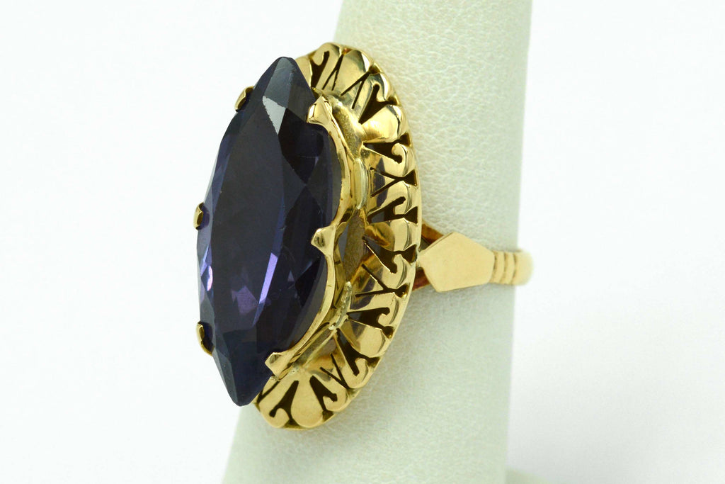 A long navette shaped amethyst ring with filigree gold accents underneath.