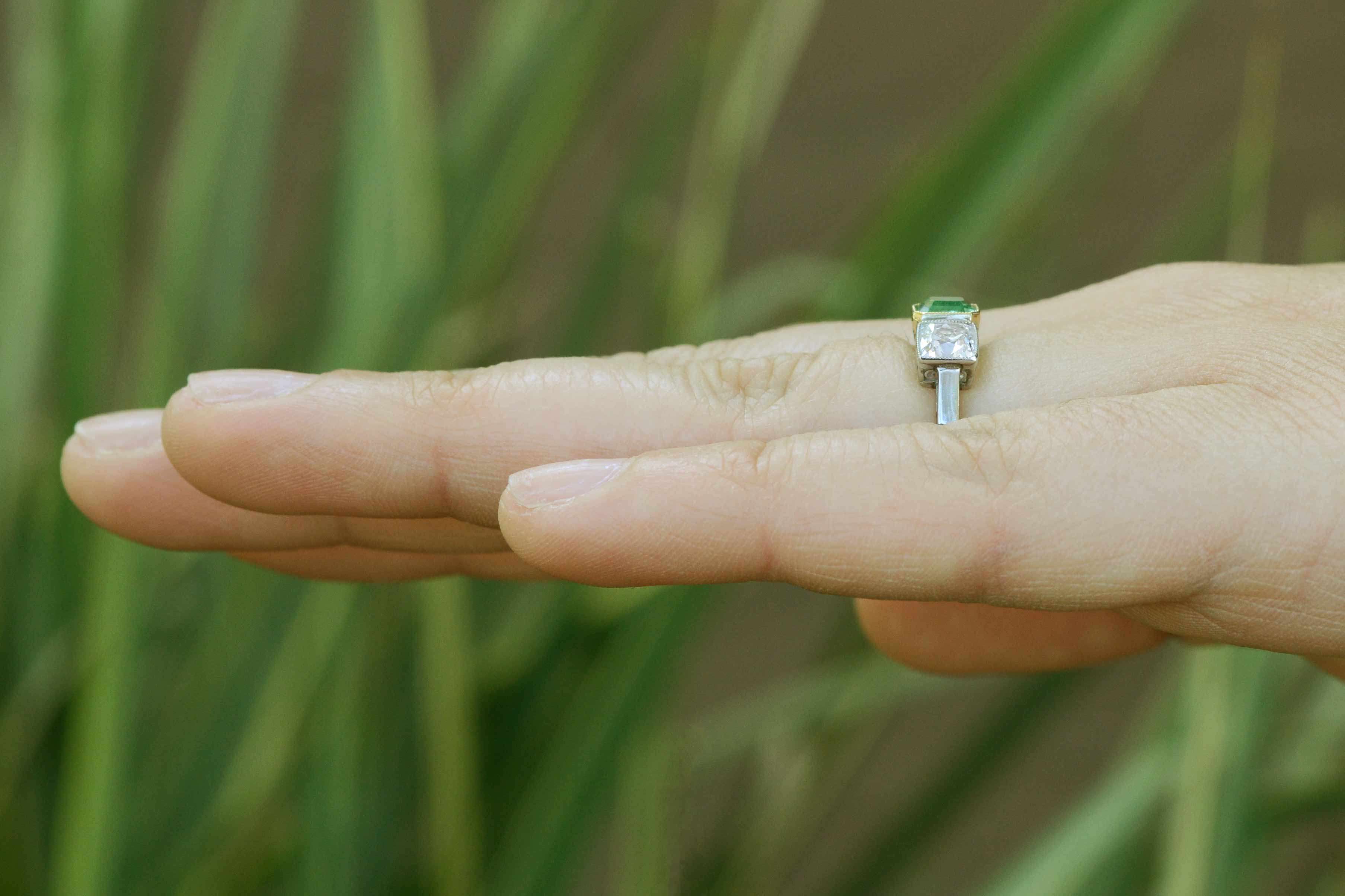 An emerald cut emerald with 2 square cushion diamonds ring.