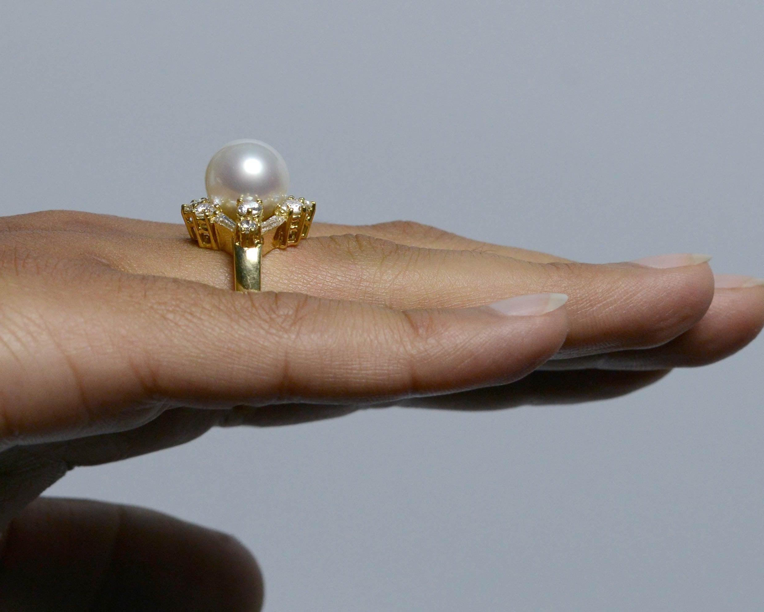 A white, natural south sea pearl in a diamonds & 18k yellow gold ring setting.
