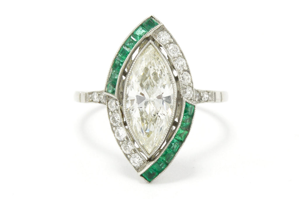 French cut emeralds accent the large marquise cut diamond in this platinum engagement ring.