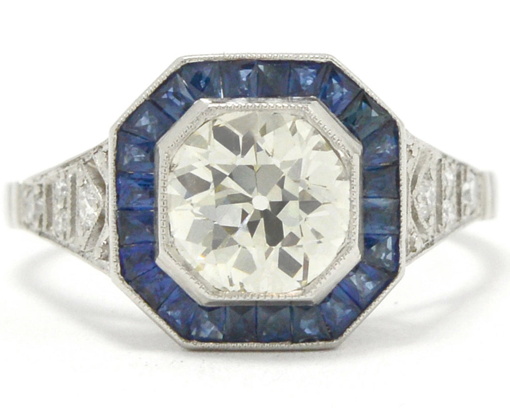 A natural old mine brilliant diamond engagment ring with a halo of blue sapphires.