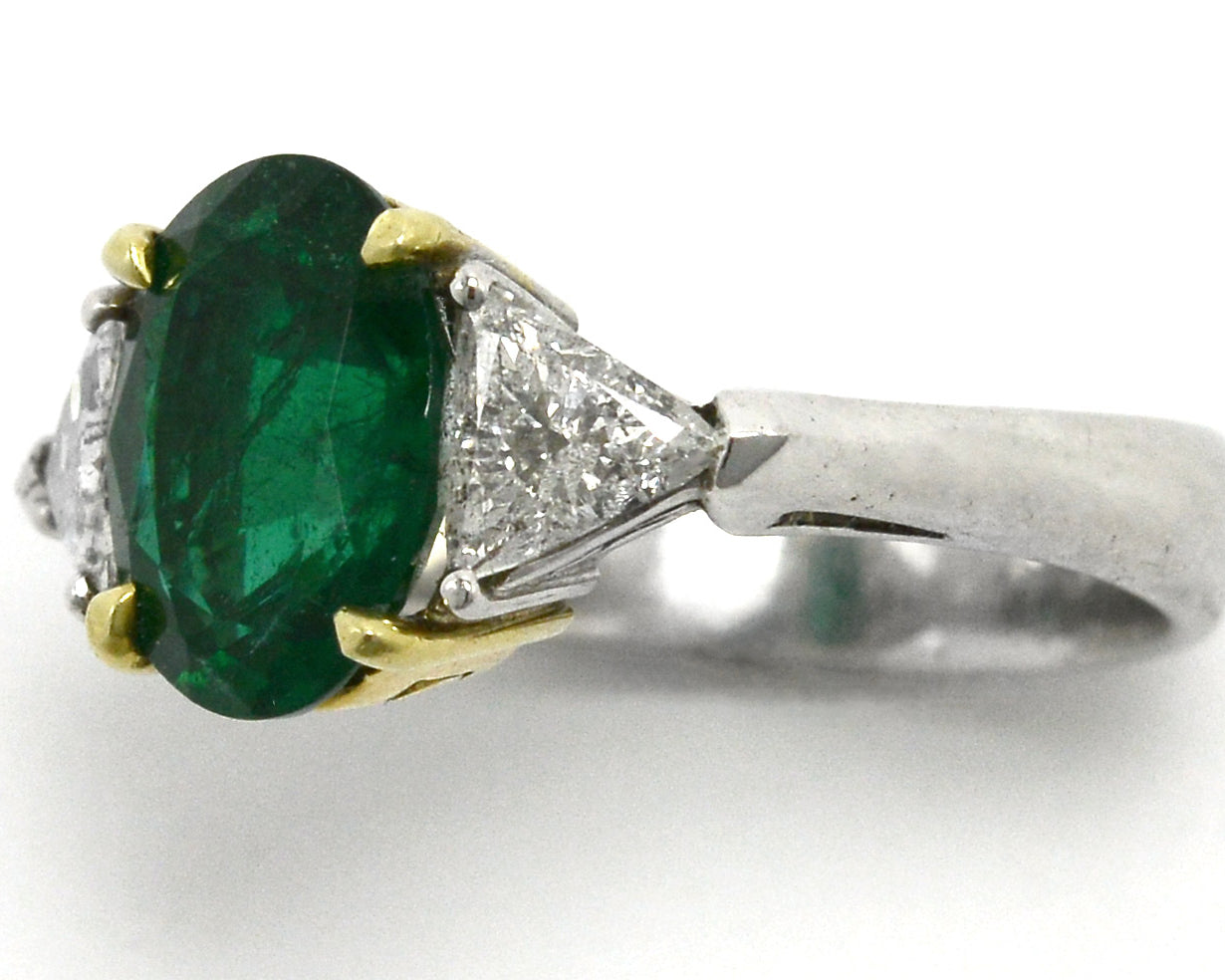 An oval emerald and 2 triangle diamond trinity ring.