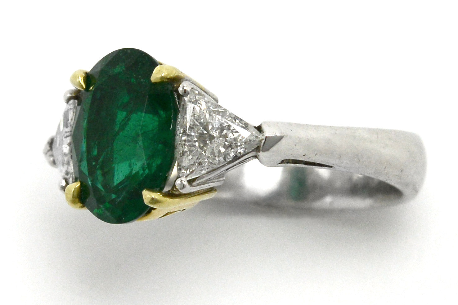 An oval emerald and 2 triangle diamond trinity ring.