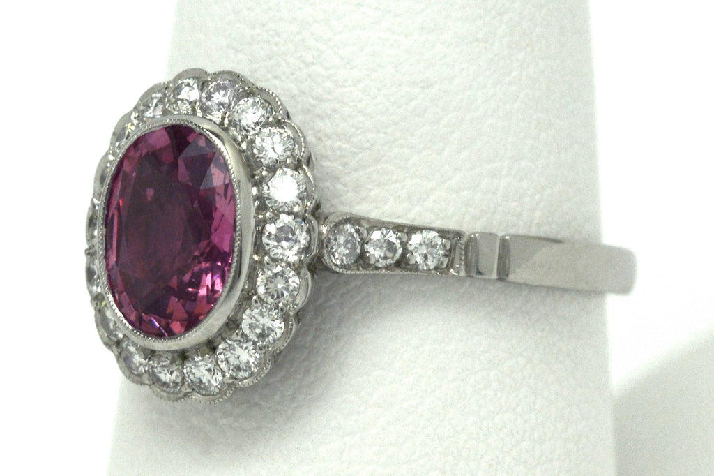 A milgrain diamond halo engagement ring, set with a natural, oval pink sapphire.