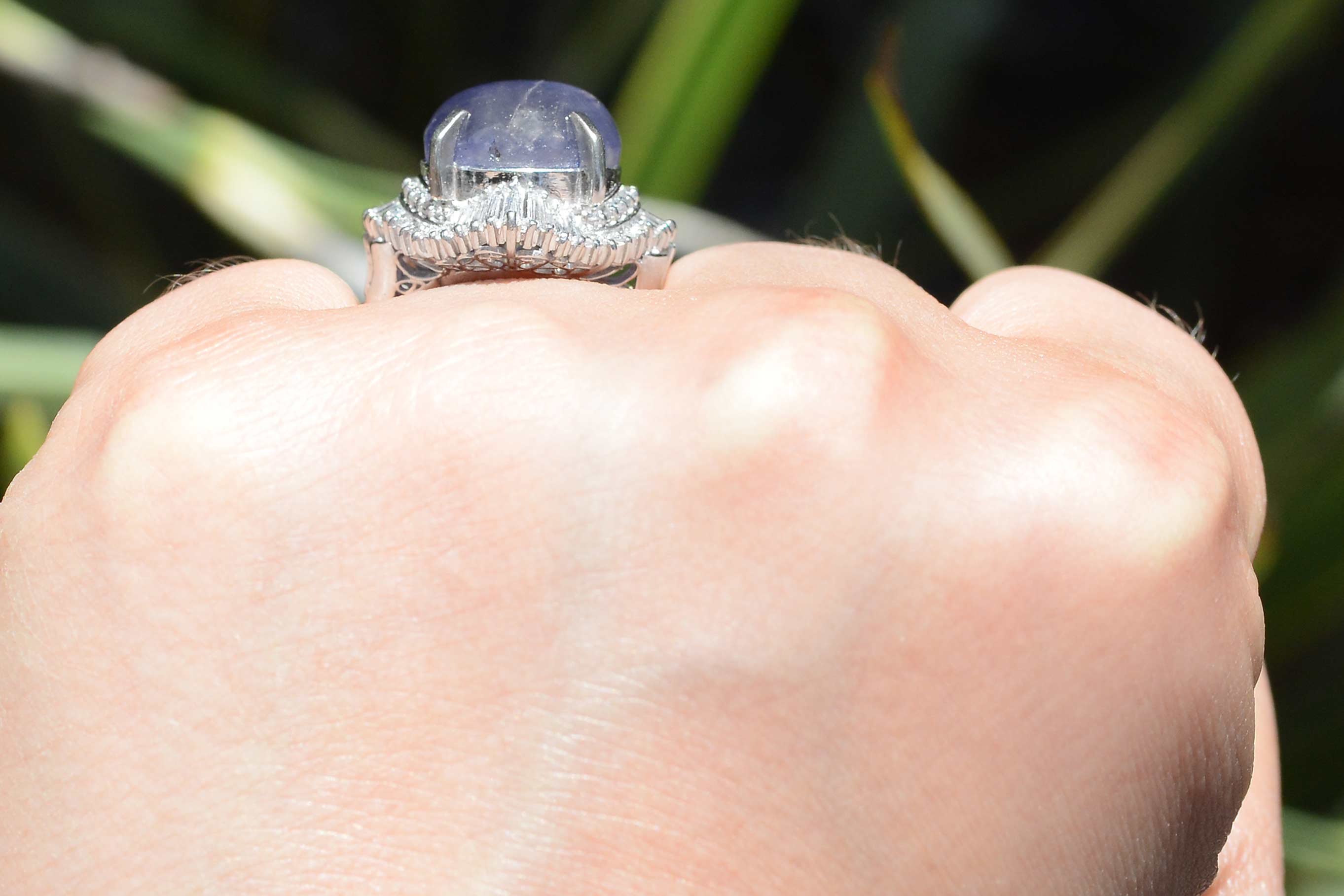 A halo of tapered baguette diamonds line this stunning purple star sapphire dome ring.