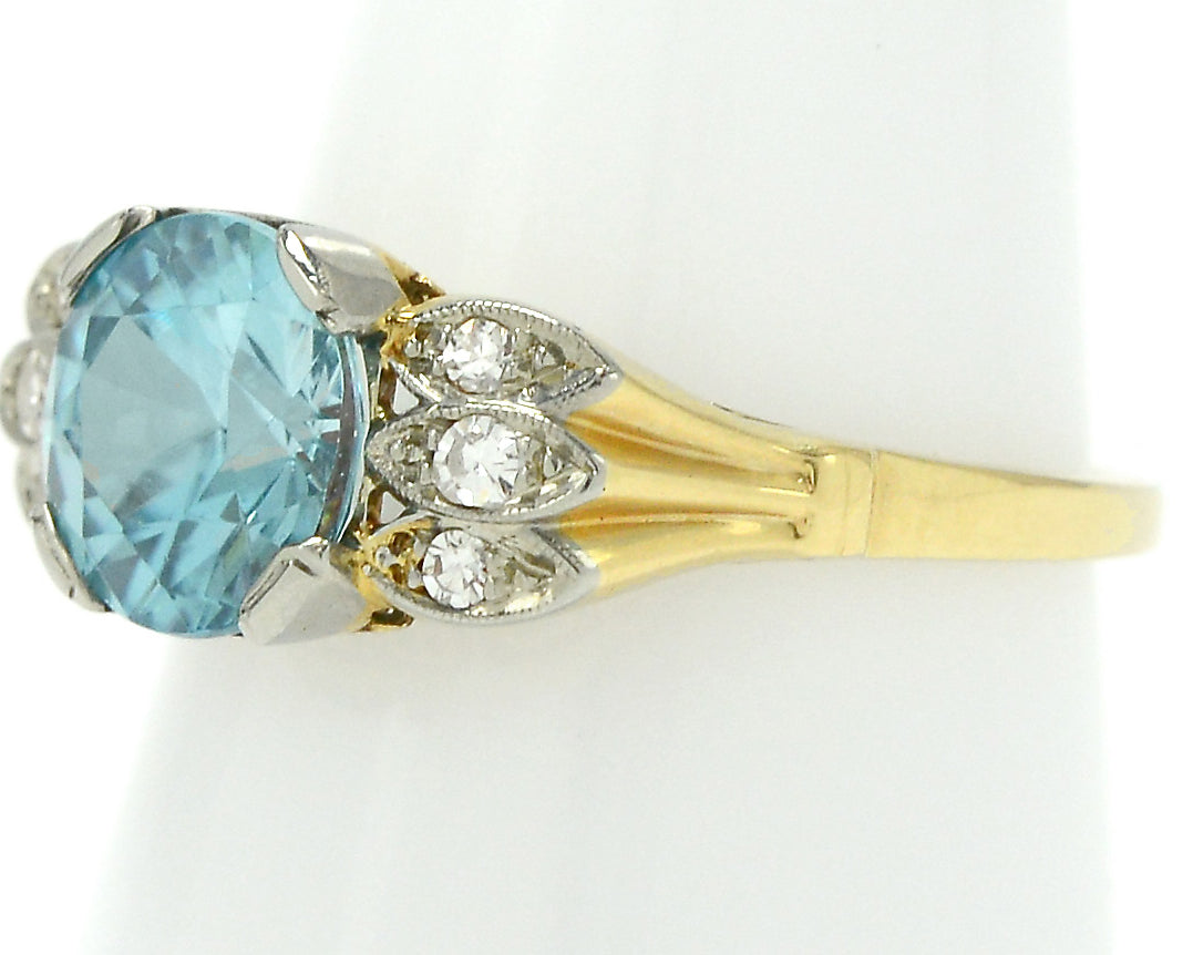 A radiating 18k gold band supporting a neon blue zircon.