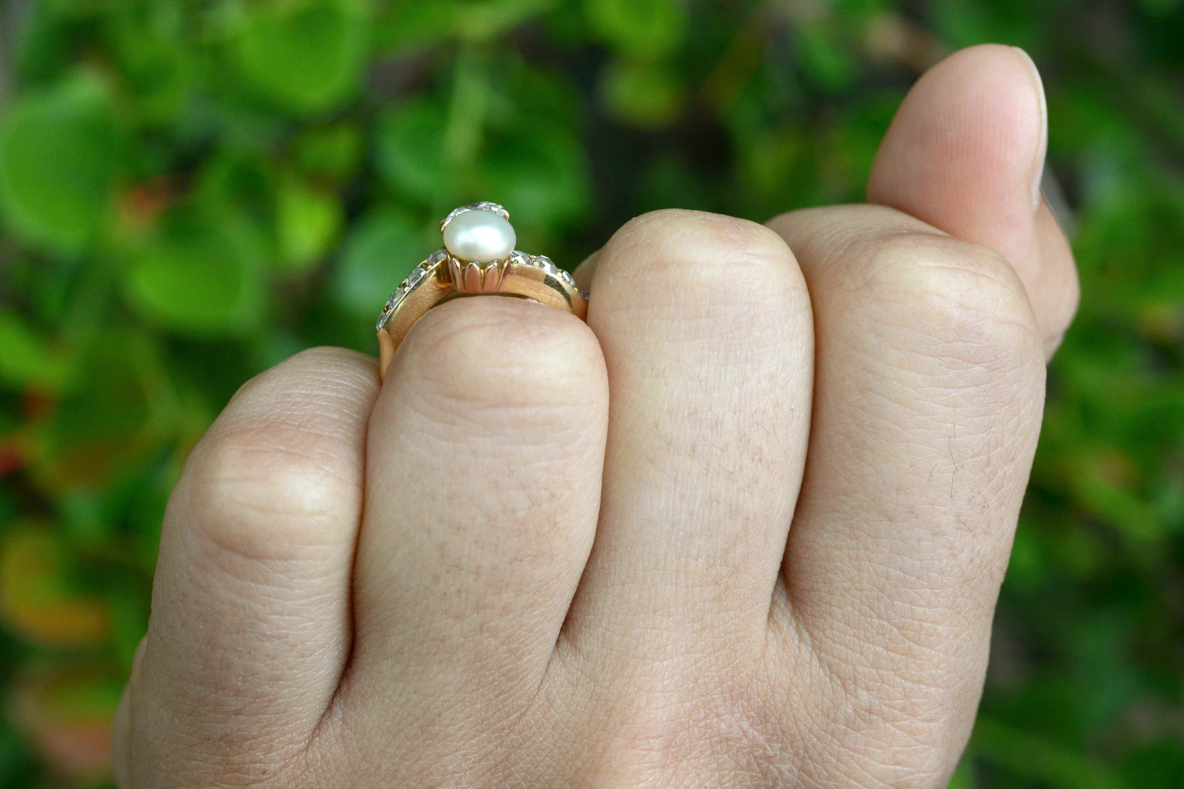 This gold solitaire ring features a pearl and diamonds.