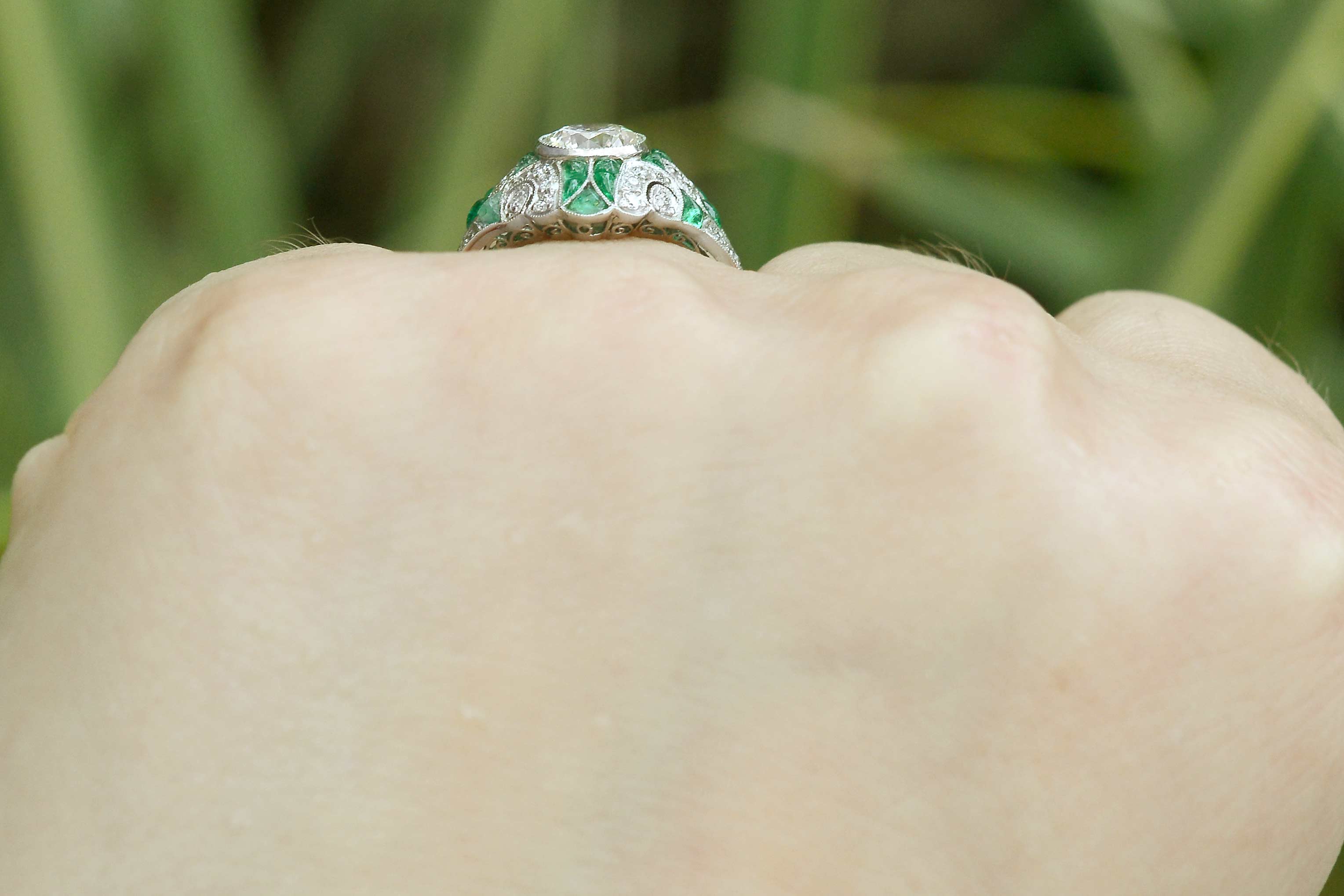 Cabochon cut emeralds line this diamond mosaic engagement ring.