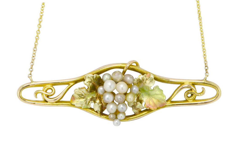 A cluster of seed pearls center an enamel grape design, gold necklace.