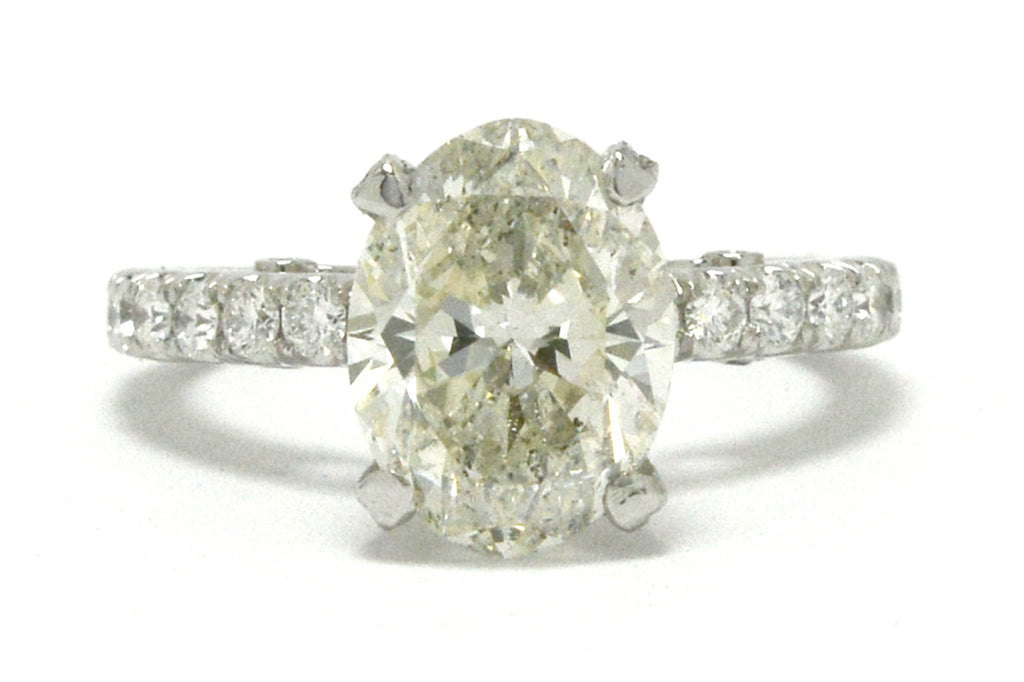 A large oval 3 carat diamond is set in a solitaire engagement ring setting.
