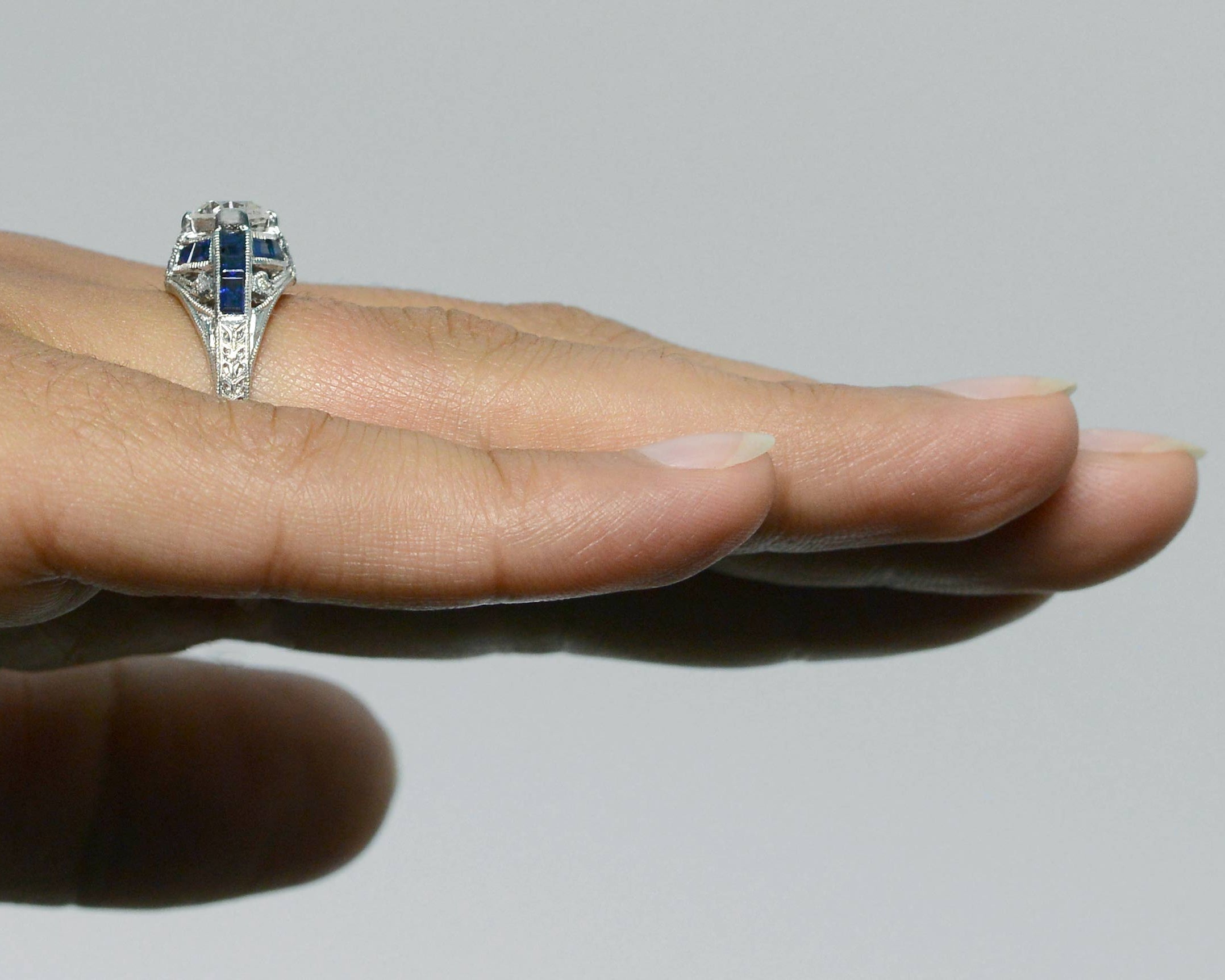 There is a blue sapphire cross pattern in this diamond Art Deco engagement ring.