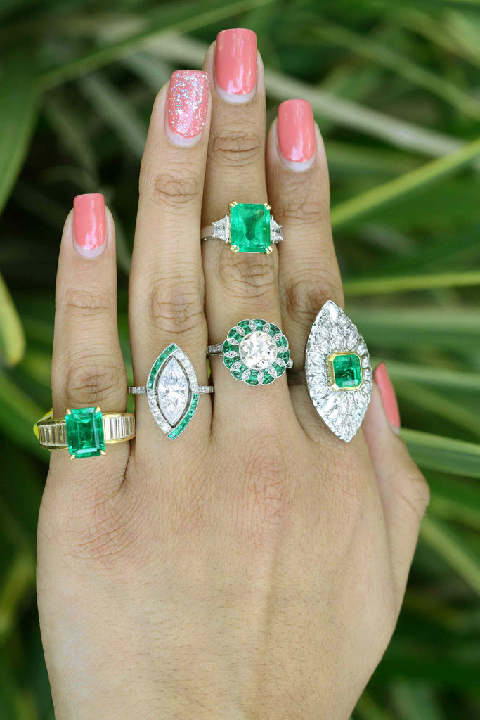 A set of engagement rings with large diamond and emerald center gemstones.